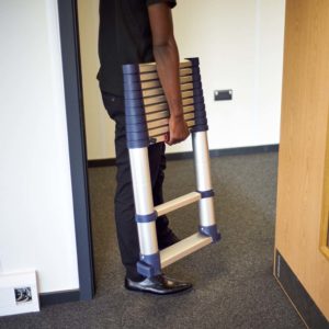 A man carrying the Xtend+Climb Telescopic Ladder through offices