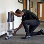 A man pulling the retractable stabiliser bars out prior to using the extending the ladder