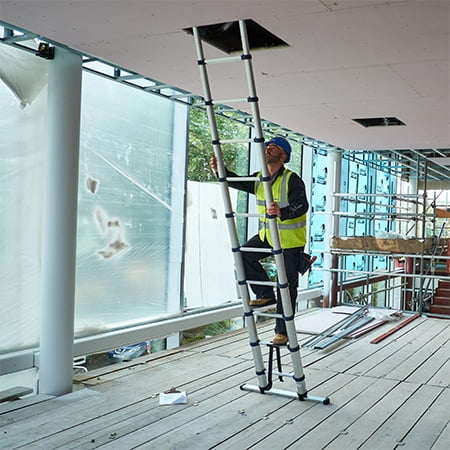 A surveyor climbing a telescopic ladder to inspect the ceiling of a new build